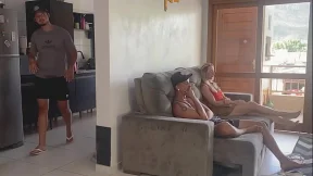 HER HUSBAND IN THE KITCHEN AND HER IN THE LIVING ROOM WITH HER FRIEND